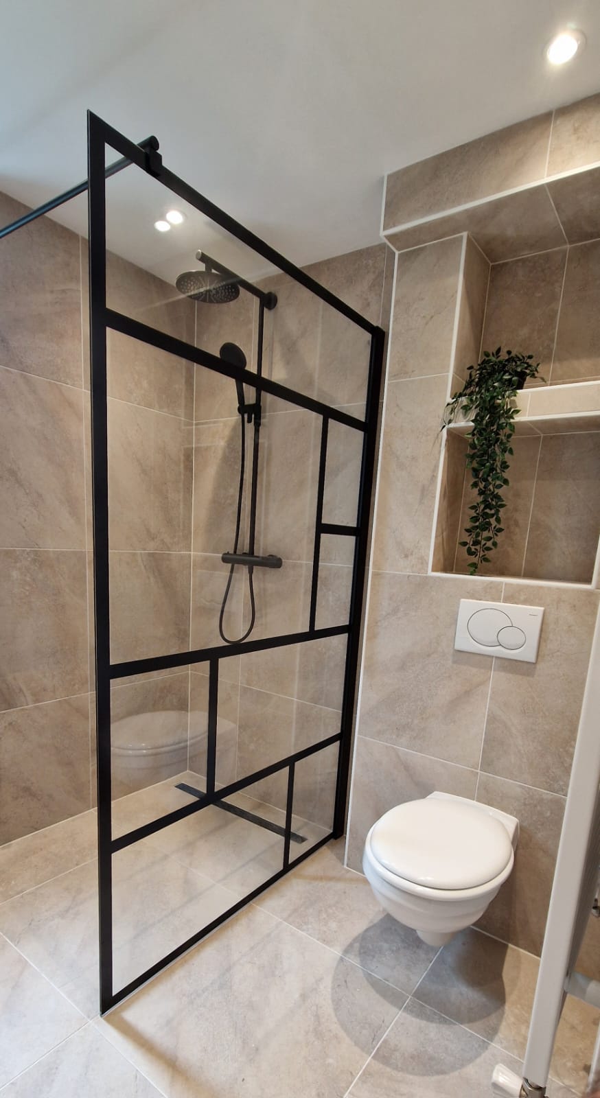 Baño reformado con mampara negra, ducha moderna y tonos beige