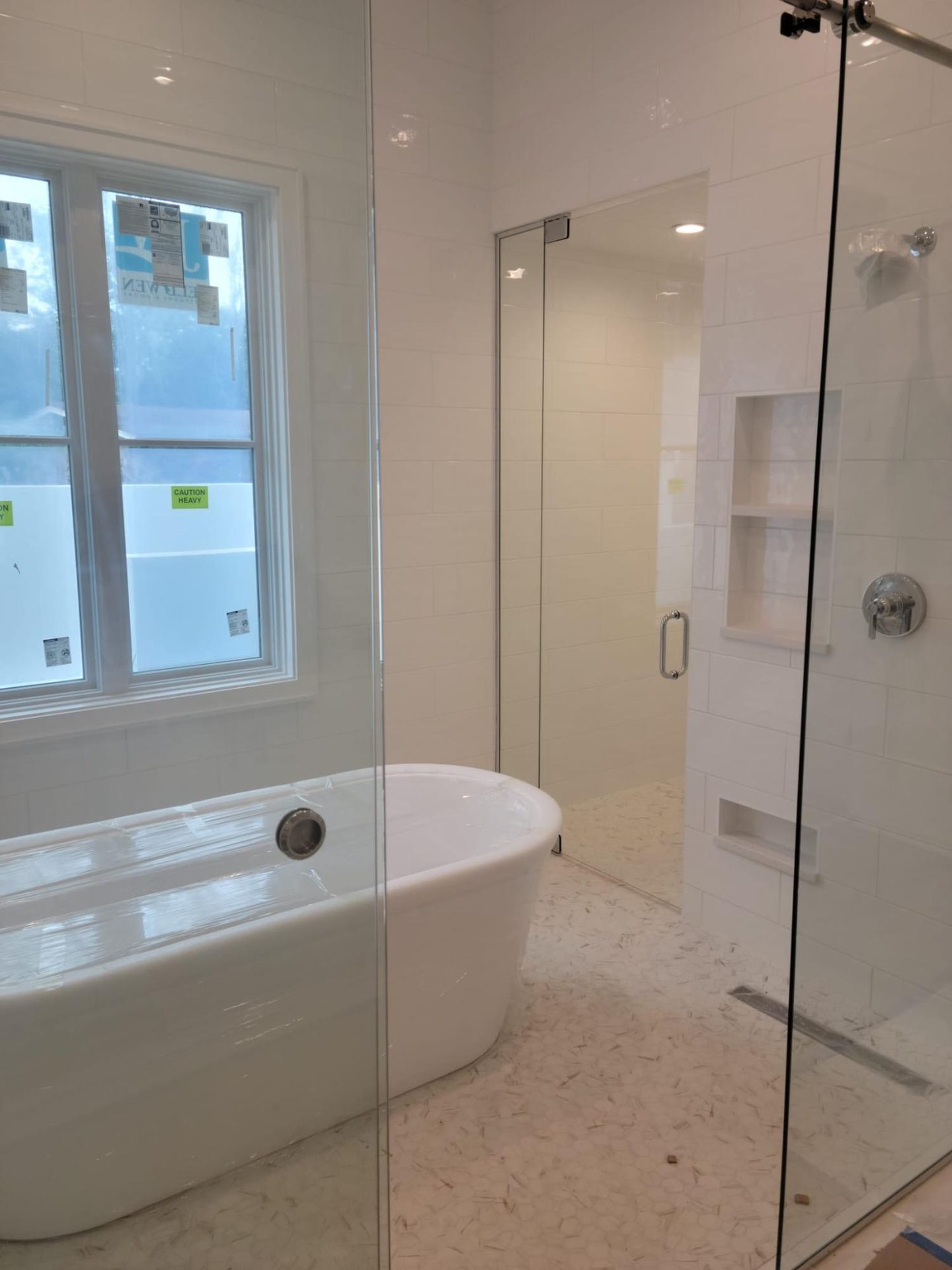 Baño blanco con bañera exenta y ducha con mampara de cristal