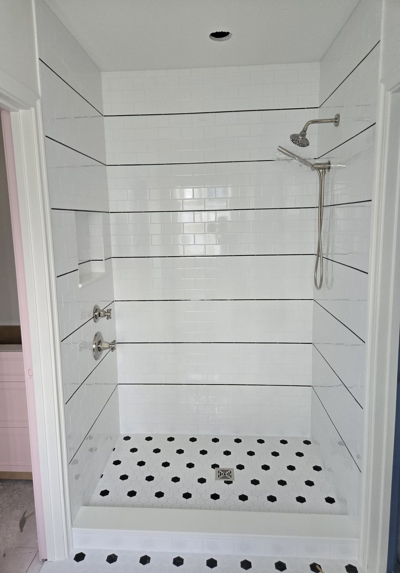 Ducha reformada con azulejo blanco tipo metro y suelo hexagonal