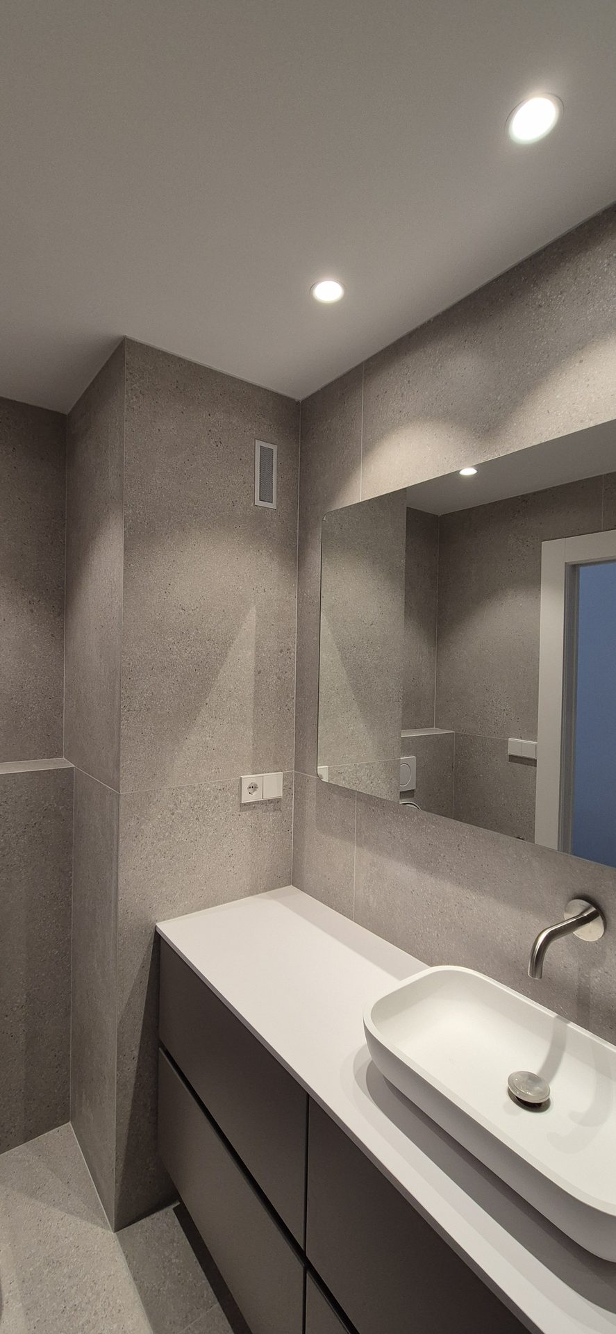 Baño reformado en tonos grises con ducha y mueble de lavabo