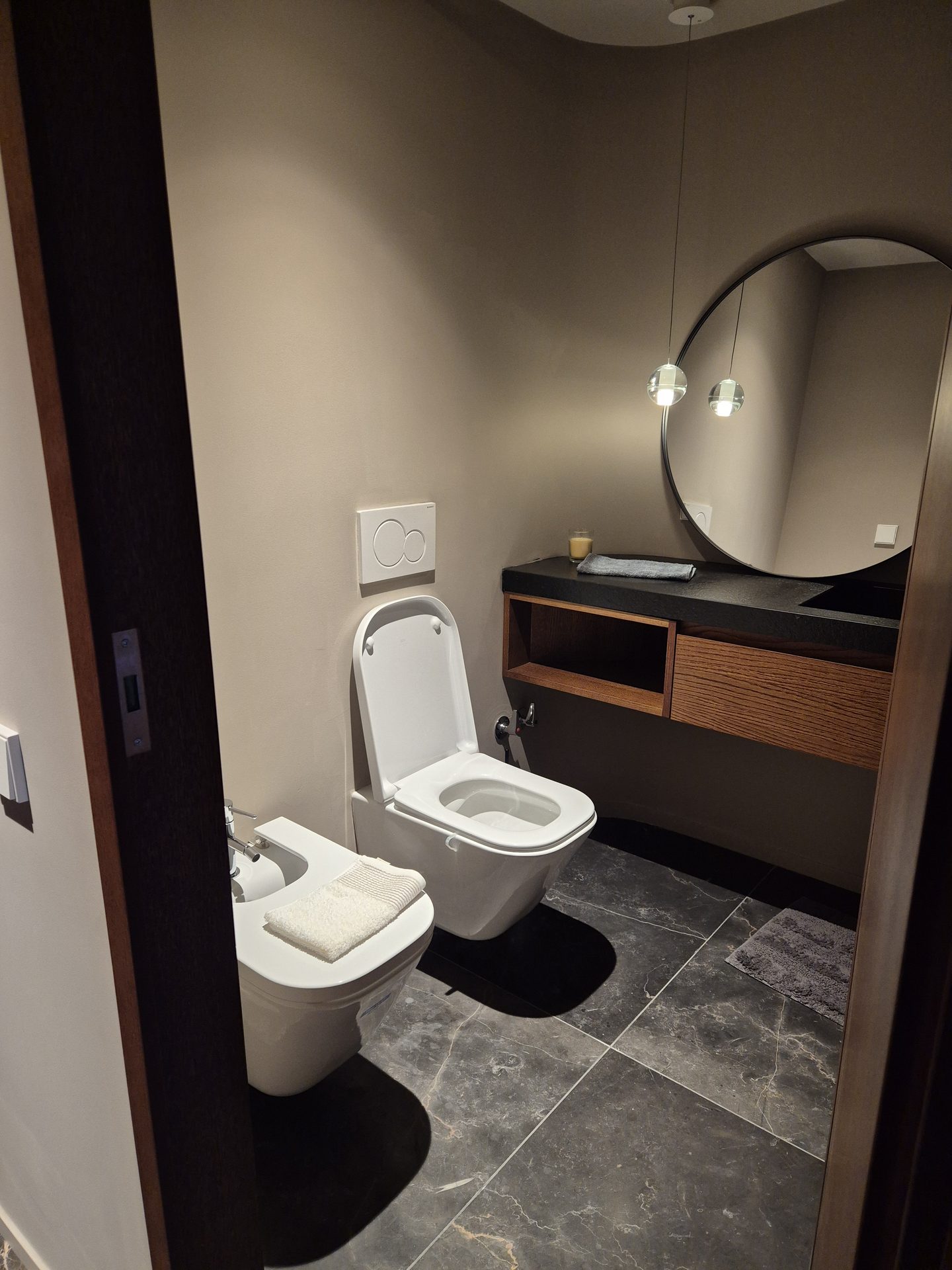 Baño moderno reformado con ducha de cristal y acabados en mármol oscuro
